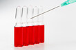 © CONQUEROR - İnjection needle in selective focus. Injection ampoules of hormone B12 out of focus.