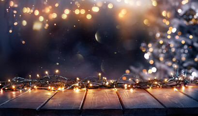 Wall Mural - christmas - defocused string light on rustic wooden table in the night with abstract tree