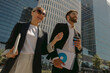 © Yaroslav Astakhov - Two colleagues is talking during break time standing on background of modern city skyscrapers
