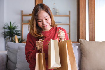 Wall Mural - Portrait image of a young woman holding and opening shopping bags at home