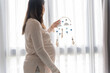 Pregnant asian woman installing baby mobile toy over the baby crib handmade toys above the newborn crib or Baby crib wood mobile