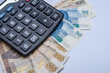 Pieniądze, polskie banknoty PLN leżą na biurku obok kalkulatora