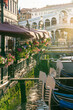 Rialto bridge with gondolas lined by restaurant terraces with flowers