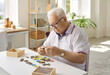 Elderly man is putting together a puzzle in a modern dementia rehabilitation center. Creative idea of memory loss training during dementia, Alzheimer's disease. The concept of human mental health.
