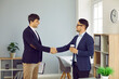 © Studio Romantic - Two people standing in the office, smiling and shaking hands. Happy young colleagues or business partners thanking each other for cooperation and exchanging handshakes