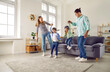 © Studio Romantic - Happy young family playing together at home in living room. Cheerful mother and father having fun with their kids. Cute little boy and girl wearing goggles jumping on sofa