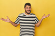 © Asier - Young Hispanic man on yellow background confused and doubtful shrugging shoulders to hold a copy space.