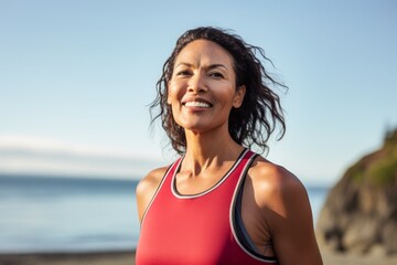 Wall Mural - Portrait of a smiling woman in her 40s dressed in a high-performance basketball jersey against a tranquil ocean backdrop. AI Generation