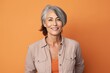 © CogniLens - Portrait of a satisfied woman in her 50s sporting a versatile denim shirt against a pastel orange background. AI Generation
