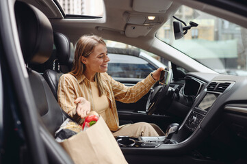 Young customer woman wear casual clothes take selfie on mobile cell phone driving car with bag of goods after shopping buying products at supermaket store grocery hypermarket. Purchasing food concept.