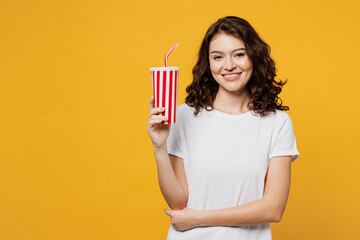 Wall Mural - Young Caucasian cheerful woman she wear white blank t-shirt casual clothes hold in hand cup of soda pop cola fizzy water isolated on plain yellow orange background studio portrait. Lifestyle concept.