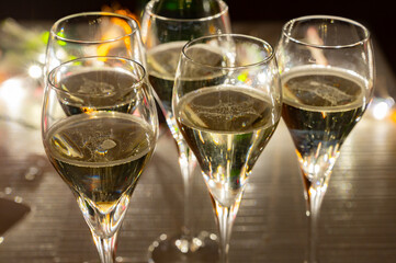 New year party, small bubbles of brut champagne cava or prosecco wine in tulip glasses with garland  lights on background