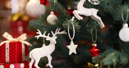 Wall Mural - christmas tree decorated with white reindeer and bright lights near the fireplace with fire