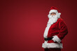 © Fxquadro - Jolly Santa Claus in traditional red suit standing with hands on hips against red backdrop