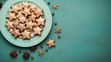  A Plate Full Of Star Shaped Cookies On Top Of A Blue Surface With Christmas Decorations Around It And On Top Of The Plate Is An Ornament Of Star Shaped Cookies.