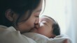Asian mother kisses and hugs her baby, blurred kids room. Mother's day concept.