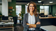 © Formoney - Portrait of a smiling businesswoman standing with arms crossed in office