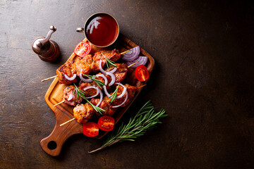 Wall Mural - Pork kebab with barbecue sauce and tomatoes on a dark background, top view copy space for text