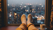 Feet in socks overlooking the city through the windows. A woman relaxes, enjoying a cup of hot drink. Close-up on the feet. The concept of winter holidays and Christmas