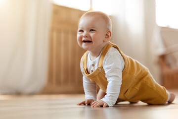 Cute little baby boy discovering world, crawling by home