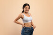 © Prostock-studio - Happy Young Indian Woman Wearing Oversized Jeans Demonstrating Weight Loss Result
