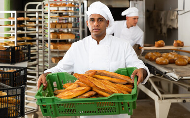 Wall Mural - Baker with box with baguettes in bakery kitchen