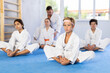 © JackF - Children in white kimono sits in a butterfly pose and practices stretching in sport gym