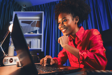 Wall Mural - African woman blogger wearing pink shirt with happy face, looking on screen laptop with valued achievement project or get scholarship. Concept of cheerful expression work from home. Tastemaker.