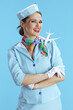 © Alliance - happy stylish female air hostess on blue