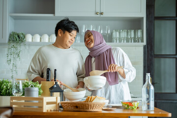 Wall Mural - Cute son And His Muslim Mom In Hijab Preparing Pastry For Cookies In Kitchen, Baking Together At Home. Islamic Lady With son Enjoying Doing Homemade Pastry, preparing to cook breakfast for her family.