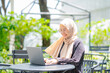 © maya1313 - Cheerful muslim lady in hijab working online at cafe, using laptop, copy space. Side view of smiling arab woman freelancer typing on laptop, enjoying her distant job, Muslim working woman concept.