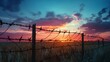 Boundary barbed wire fence in the territory military zone with dawn and sunset background. International International Holocaust Remembrance Day sunlight with silhouette on meadow defense background.