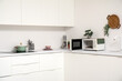 © Pixel-Shot - Interior of light kitchen with microwave oven, electric stove and utensils on white counters