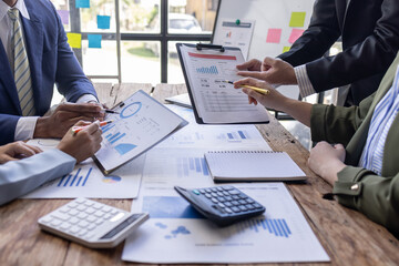 Group of confident business people point to graphs and charts to analyze market data, balance sheet, account, net profit to plan new sales strategies to increase production capacity.	