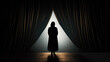 © Vivid Pixels - Silhouette from behind of a woman on stage looking out between parted curtains