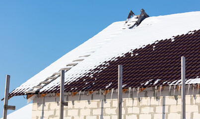 Wall Mural - Roof of a house covered in snow against a blue sky