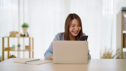 Funny euphoric young asian woman celebrating winning or getting ecommerce shopping offer on computer laptop. Excited happy girl winner looking at notebook celebrating success