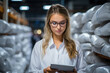 © Ai-Pixel - Portrait of female factory worker wearing glasses and white robe, pressing machine buttons, using tablet for quality control and logistic purposes at polymer plastic manufacturing
