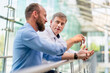© Westend61 - Colleagues discussing innovative business solutions leaning standing in office corridor