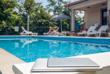Laptop And Tablet PC Kept Near Swimming Pool On Sunny Day