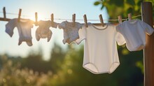 Photograph Of White Baby Clothes Hanging On Laundry Line Outdoors.