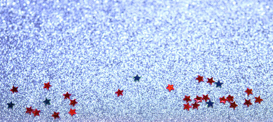 Red and blue stars of confetti on a blue cold blurred snowy background. Brilliant colored sequins. Holiday greeting card. Happy holidays. Minimal, flat lay, copy space. Mockup