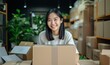 © Viewvie - Portrait of young asian woman smiling while unpacking cardboard boxes in office