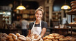Baker woman standing with fresh breads in background. Happy woman standing in her bake shop and looking at camera.