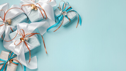 Wall Mural - Gift boxes wrapped in blue, white and silver paper with white, blue and gold ribbon bows. Blue background, top view. Christmas and New Year gifts, Boxing Day.