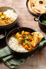 Poster - Chicken curry with long rice and naan bread in a dark bowl. Indian style dinner. Vertical image.