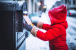 A Child in a red jacket and gloves is sending a letter from a mailbox. Selective focus