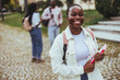 Cheerful African American Female Student With Smartphone And Workbooks Standing Outdoors, Happy Woman Walking In City After College Classes, Looking Away And Smiling, Copy Space