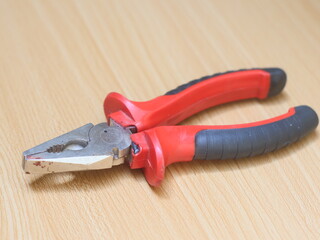 An iron pliers lies on a wooden patterned background