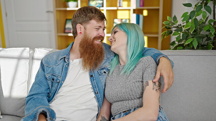 Poster - Man and woman couple hugging each other sitting on sofa at home